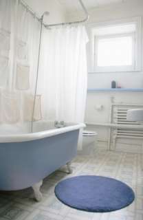 Claw foot bathtub with a round blue bath rug
