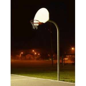 Basketball Net and Court Illuminated at Night in a Residential Area 